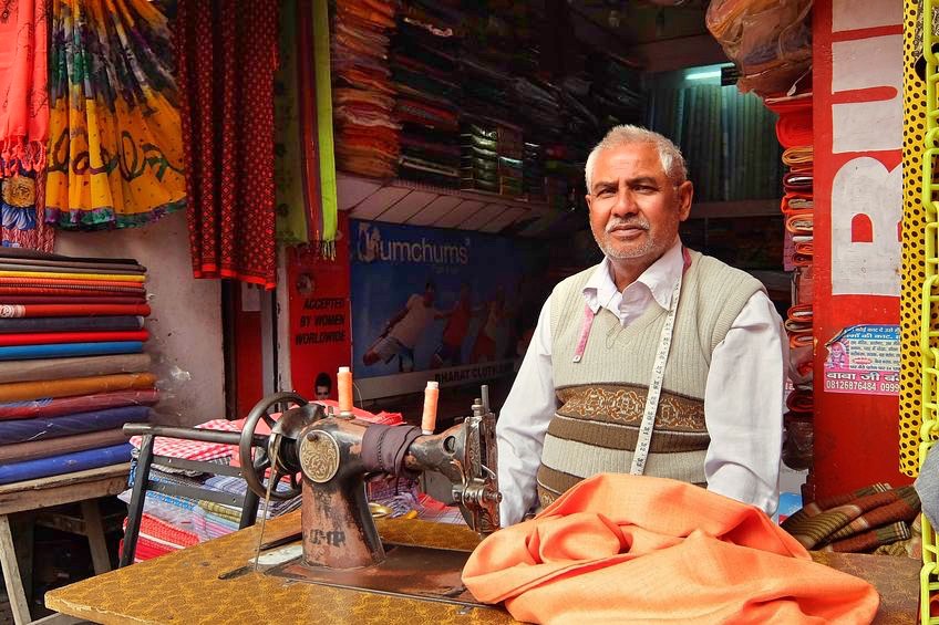 96423273 - haridwar, india - november, 6th, 2017. man's clothes on sewing machine in his workshop at the local market near the har ki pauri in haridwar.